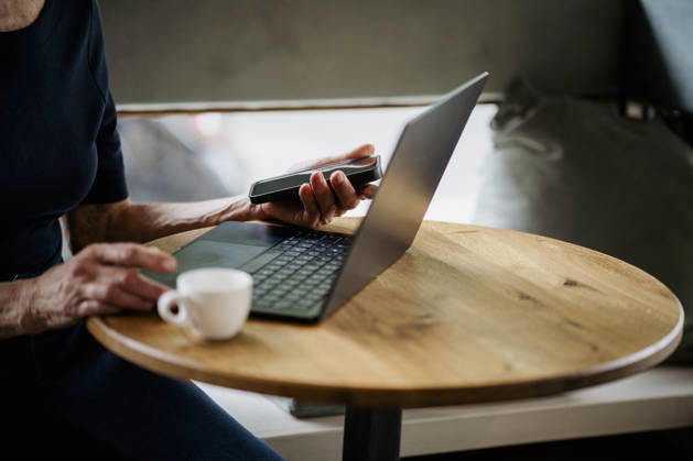 Person using laptop and smartphone at café table with coffee model released, Symbolfoto property released, KNSF12169