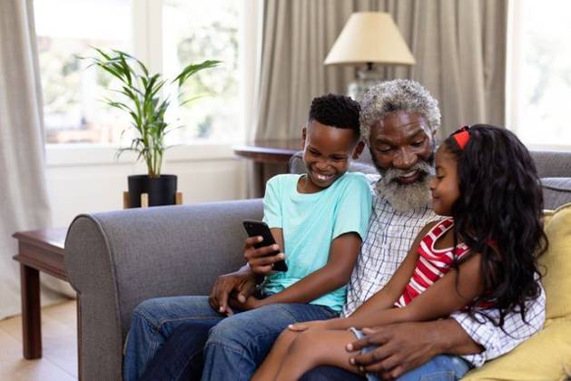 Senior African American man and his grandchildren enjoying their time at home Senior African American man and his grandchildren enjoying their time at home together, sitting on a couch, embracing, smiling, using a smartphone, model released, , property released, Cape Town, South Africa, 19.02.2020, 1340051.jpg, people,family,grandfather,granddad,granddaughter,grandson,siblings,brother,sister,childhood,together,closeness,interacting,sitting,couch,holding,using,phone,mobile phone,smartphone,connection,communication,real people,home,house,domestic life,lifestyle,enjoying,free time,leisure,relaxing,weekend,summer,sunny,love Child,Girl,Female,Mixed-Race,Boy,Male,Black,Mid Adult,Man Indoors,Side view,Day,Three Quarter Length