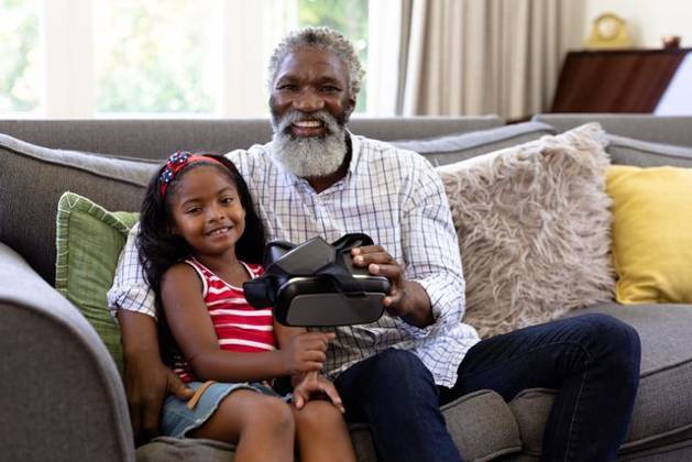 Senior African American man and his granddaughter using vr headset Senior African American man and his granddaughter enjoying their time at home together, sitting on a couch, holding a VR headset, looking at the camera and smiling, model released, , property released, Cape Town, South Africa, 19.02.2020, 1340099.jpg, people,family,grandfather,granddad,granddaughter,childhood,together,closeness,interacting,sitting,couch,happy,smiling,holding,vr,virtual reality,headset,connection,communication,real people,home,house,domestic life,lifestyle,enjoying,free time,leisure,relaxing,weekend,summer,sunny,love Child,Girl,Female,Mixed-Race,Mid Adult,Man,Male,Black Indoors,Side view,Looking at camera,Day,Three Quarter Length