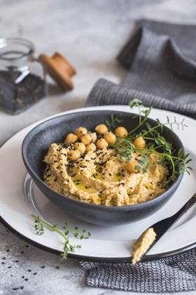 Kichererbsenhummus in der schwarzen Schale, dekoriert mit Sesamsamen und Kichererbsengrün. Vegane Rezepte, Gerichte auf pflanzlicher Basis. Konzept für umweltfreundliches Wohnen. Biologische Lebensmittel. Vegetarische Küche Chickpeas hummus in the black bowl decorated with sesame seeds and chickpeas greens. Vegan recipes, plant-based dishes. Green living concept. Organic food. Vegetarian cuisine Copyright: imageBROKER NataliiaxZhekova ibxiqx16147410