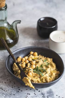 Kichererbsenhummus in der schwarzen Schale, dekoriert mit Sesamsamen und Kichererbsengrün. Vegane Rezepte, Gerichte auf pflanzlicher Basis. Konzept für umweltfreundliches Wohnen. Biologische Lebensmittel. Vegetarische Küche Chickpeas hummus in the black bowl decorated with sesame seeds and chickpeas greens. Vegan recipes, plant-based dishes. Green living concept. Organic food. Vegetarian cuisine Copyright: imageBROKER NataliiaxZhekova ibxiqx16147414