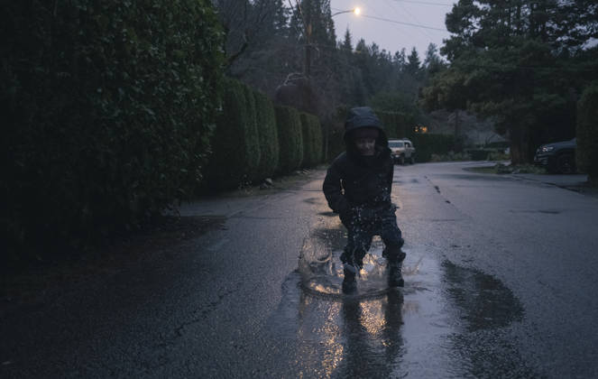 Young boy jumps and splashes in puddle on rainy day in the fall West Vancouver, British Columbia, Canada CR_PSFZ260305B-1958580-01 ,model released, Symbolfoto
