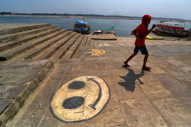 February 28, 2026, Varanasi, Uttar Pradesh, India: A man walks past a street mural depicting a smiley emoji. Varanasi India - ZUMAs197 20260228_aab_s197_064 Copyright: xAvishekxDasx