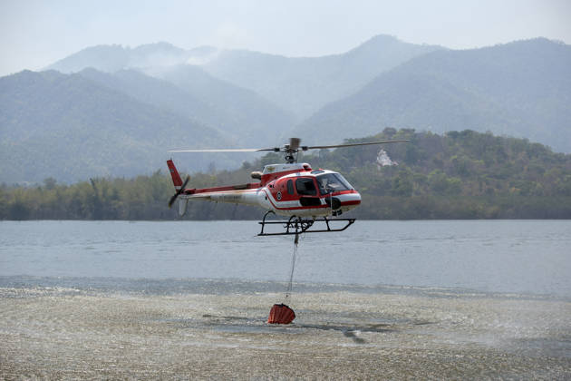March 27, 2026, Chiang Mai, Thailand: A helicopter performs water pickup operations over a reservoir in Chiang Mai, northern Thailand, as part of aerial firefighting efforts against ongoing wildfires. An AS350 helicopter from the Ministry of Natural Resources and Environment skims the water surface to collect water before heading to fire-affected forest areas amid hazy conditions caused by smoke and rising PM2.5 pollution. Chiang Mai Thailand - ZUMAs197 20260327_aaa_s197_312 Copyright: xPongmanatxTasirix