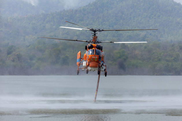 March 27, 2026, Chiang Mai, Thailand: A helicopter performs water pickup operations over a reservoir in Chiang Mai, northern Thailand, as part of aerial firefighting efforts against ongoing wildfires. A KA-32 helicopter from the Department of Disaster Prevention and Mitigation skims the water surface to collect water before heading to fire-affected forest areas amid hazy conditions caused by smoke and rising PM2.5 pollution. Chiang Mai Thailand - ZUMAs197 20260327_aaa_s197_339 Copyright: xPongmanatxTasirix