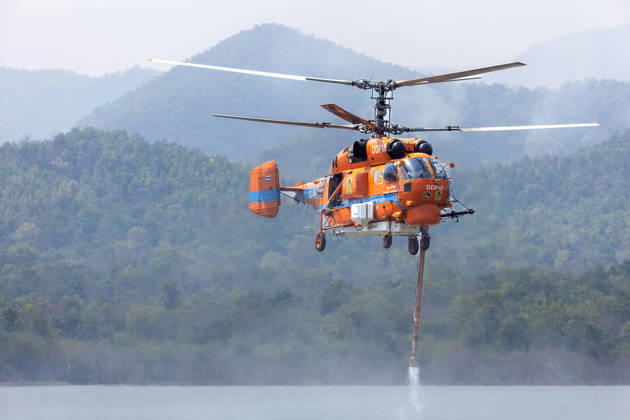 March 27, 2026, Chiang Mai, Thailand: A helicopter performs water pickup operations over a reservoir in Chiang Mai, northern Thailand, as part of aerial firefighting efforts against ongoing wildfires. A KA-32 helicopter from the Department of Disaster Prevention and Mitigation skims the water surface to collect water before heading to fire-affected forest areas amid hazy conditions caused by smoke and rising PM2.5 pollution. Chiang Mai Thailand - ZUMAs197 20260327_aaa_s197_342 Copyright: xPongmanatxTasirix