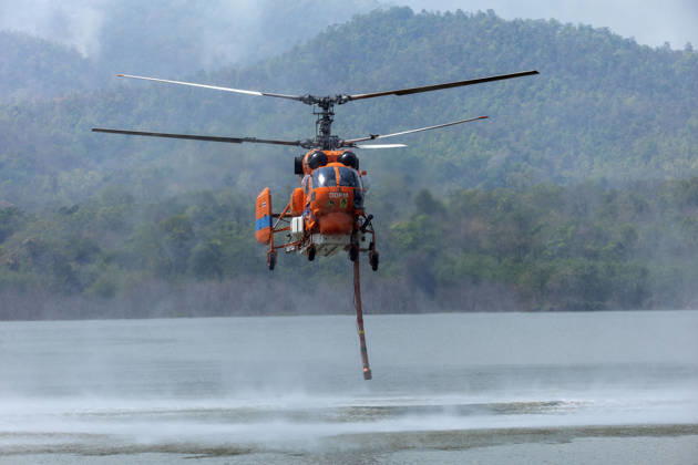 March 27, 2026, Chiang Mai, Thailand: A helicopter performs water pickup operations over a reservoir in Chiang Mai, northern Thailand, as part of aerial firefighting efforts against ongoing wildfires. A KA-32 helicopter from the Department of Disaster Prevention and Mitigation skims the water surface to collect water before heading to fire-affected forest areas amid hazy conditions caused by smoke and rising PM2.5 pollution. Chiang Mai Thailand - ZUMAs197 20260327_aaa_s197_369 Copyright: xPongmanatxTasirix