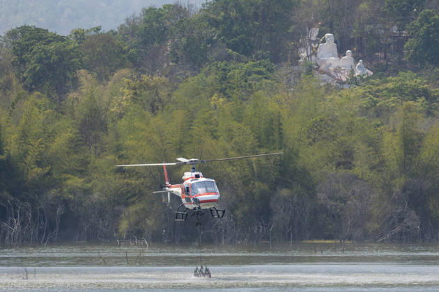 March 27, 2026, Chiang Mai, Thailand: A helicopter performs water pickup operations over a reservoir in Chiang Mai, northern Thailand, as part of aerial firefighting efforts against ongoing wildfires. An AS350 helicopter from the Ministry of Natural Resources and Environment skims the water surface to collect water before heading to fire-affected forest areas amid hazy conditions caused by smoke and rising PM2.5 pollution. Chiang Mai Thailand - ZUMAs197 20260327_aaa_s197_379 Copyright: xPongmanatxTasirix
