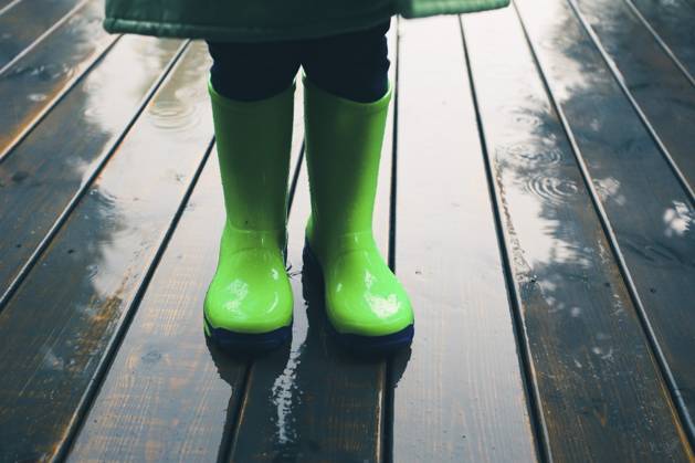 Nahaufnahme der Beine eines Kindes, das auf einer Veranda steht und grüne Gummistiefel und Regenmantel trägt. Regenstiefel in hellgrüner Farbe Closeup of legs of kid standing on a porch wearing green wellies and raincoat. Rain boots in bright green color Copyright: imageBROKER PrzemekxKlos ibxiqx16931953.jpg ,model released, Symbolfoto ,property released