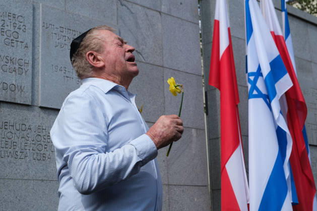 April 19, 2026, Warsaw, Masovian Voivodeship, Poland: A commemorator holding a daffodil sings at the Umschlagplatz Monument in Warsaw during official commemorations of the 83rd anniversary of the outbreak of the Warsaw Ghetto Uprising. The tradition of using yellow daffodils as symbols of remembering Jewish lives lost during the uprising was started by Marek Edelman, one of the commanders of the uprising and a co-founder of the Jewish Combat Organization, an armed anti-fascist Jewish resistance movement instrumental in opposing Nazi rule in the ghetto. Warsaw Poland  - ZUMAk204 20260419_zip_k204_038 Copyright: xRomanxKozielx