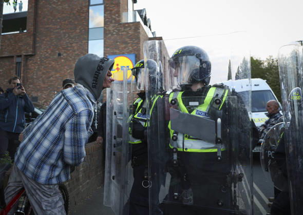 April 20, 2026, Epsom, Surrey, UK: Epsom, UK. A protester taunts police in riot gear as a large crowd gathers in Epsom, Surrey, asking for transparency and accountability from the police regarding a recent alleged gang rape in the town. Epsom UK  - ZUMAl94_ 20260420_zaf_l94_096 Copyright: xJacquelinexLawriex