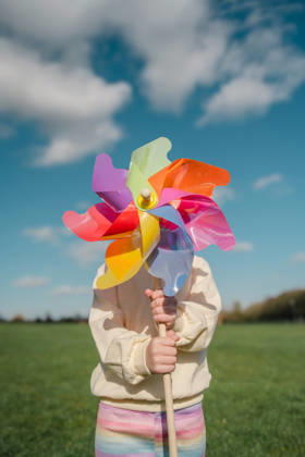 Child holding colorful pinwheel toy at the park on a sunny day model released, Symbolfoto, IGEF00867