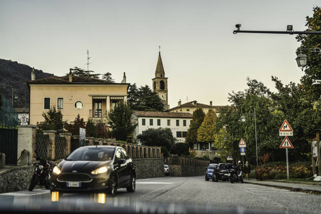 Vo, italy 28 october 2025: view of an italian village street at dusk, with an active moving car and a church bell tower rising above traditional buildings Italian village street at dusk with passing car Copyright: xx giro (245)