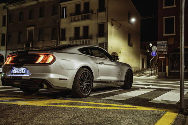 Vo, italy 28 october 2025: silver ford mustang muscle car parked on city street at night, sleek urban lifestyle shot with lit buildings and wet asphalt reflections Ford mustang parked on urban crosswalk at night Copyright: xFilippoxCarlotx giro (314)