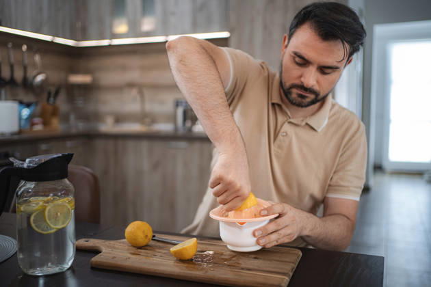Ein Mann, der in der Küche Zitronen auspresst, um Entgiftungswasser oder Limonade zuzubereiten Mid adult man squeezing lemons in the kitchen preparing detox water or lemonade (License=RF) ,model released, Symbolfoto Copyright: xZoonar.com JelenaxCvetkovicx 24952273 ,model released, Symbolfoto ,property released