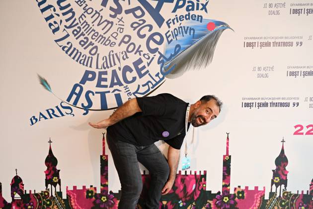 April 29, 2026, Diyarbakir, Turkey: Kurdish theater actor Sena Ozbey is seen in front of the festival billboard, holding the festival logo, which is composed of the word peace in various languages from around the world. ozbey said, The burden of peace is very heavy. The 11th Amed International Theater Festival, organized by the Diyarbakir Metropolitan Municipality and the Amed City Theater from April 22 to May 2, featured theater companies from 19 countries and 22 performances. Diyarbakir Turkey  - ZUMAs197 20260429_aab_s197_030 Copyright: xMehmetxMasumxSuerx