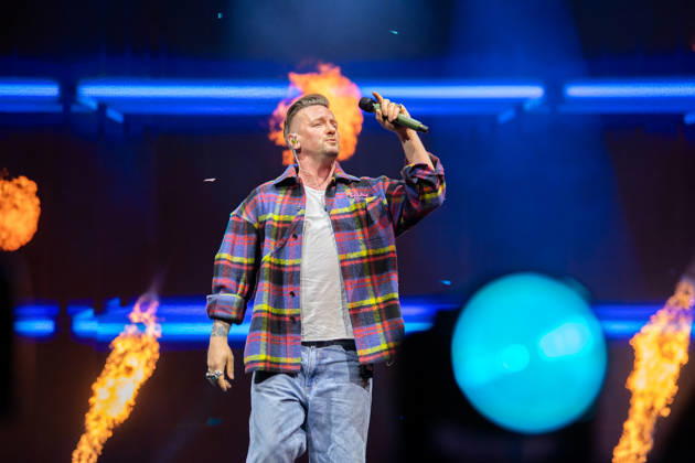 Sänger Ben Zucker performt auf der Bühne bei der Schlagernacht des Jahres in der LANXESS arena in Köln, umgeben von Flammeneffekten und farbigen Lichteffekten. Köln, Lanxess Arena NRW DE