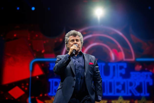 Andy Borg singt mit Mikrofon vor einer bunt beleuchteten Bühnendekoration während der Schlagernacht des Jahres in der Kölner LANXESS arena. Köln, Lanxess Arena NRW DE