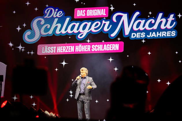 RECORD DATE NOT STATED Andy Borg steht mit Mikrofon auf der Bühne vor einer Leinwand mit dem Schriftzug Die Schlagernacht des Jahres DAS ORIGINAL lässt Herzen höher schlagen. Köln, Lanxess Arena NRW DE