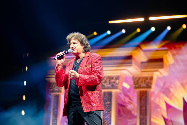 Olaf der Flipper trägt ein glitzerndes rotes Sakko und singt mit Mikrofon auf der Bühne, dahinter bunte Lichteffekte und Bühnendekoration. Köln, Lanxess Arena, 09.05.2026 NRW DE