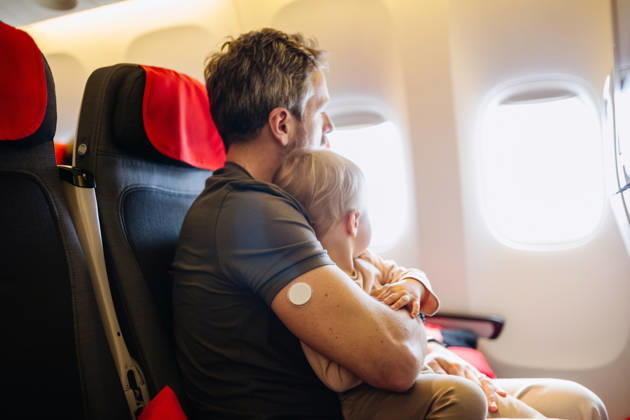 Diabetic father takign care of toddler during family flight. Diabetic father takign care of toddler during family flight. Traveling on airplane. model released
