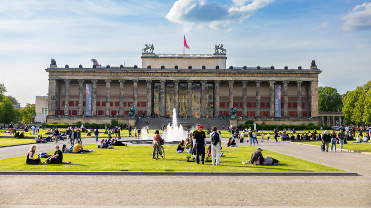 Altes Museum Berlin Lustgarten mit Brunnen und Frühlingstreiben, Berlin, 10.05.2026 Frontansicht des Alten Museums am Lustgarten in Berlin-Mitte mit dem Brunnen im Vordergrund. Zahlreiche Menschen erholen sich auf der Rasenfläche im Frühlingssonnenschein. An der Säulenfassade sind Banner zur Ausstellung Antike zu sehen. Berlin-Mitte Berlin Deutschland