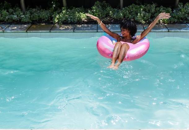 African American woman floating on pink donut float in blue pool wearing bikini, copy space, model released, property released, 26.02.2025 06:00:00, 13157771 Copyright: xIMS-260421_3xcreatorid:x166x 13157771