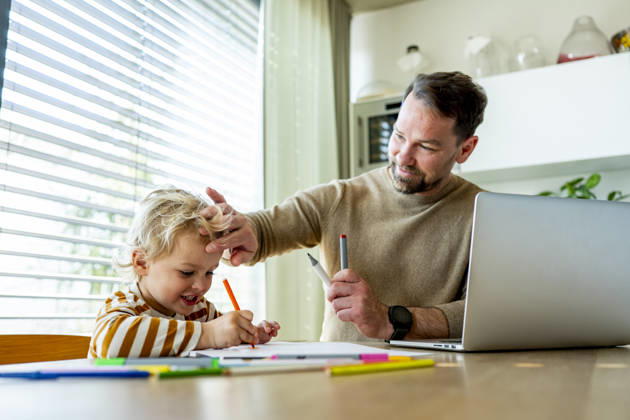 Remote working dad taking care of ill child during home office day. Father working from home while caring for sick toddler staying home from daycare. model released