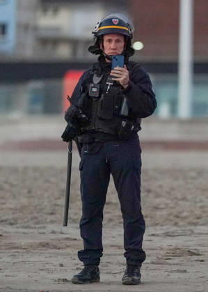 May 23, 2026, Dunkirk, Nord, France: Dunkirk, France. A police officer filming on a mobile phone as migrants attempts to board an inflatable boat at the beach at Dunkirk, to cross the English Channel. More than 200,000 migrants have crossed the Channel in small boats since 2018. Dunkirk France  - ZUMAl94_ 20260523_zaf_l94_034 Copyright: xIoannisxAlexopoulosx