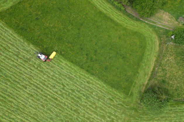 Luftaufnahme. Fruehling (Frühling) im Siegerland. Eine saftig gruene (grüne) Wiese wird von einem Traktor mit einem Maehwerk (Mähwerk) bei Siegen-Oberschelden gemaeht (gemäht). Fruehling (Frühling) im Siegerland am 23.05.2026 in Siegen Deutschland.