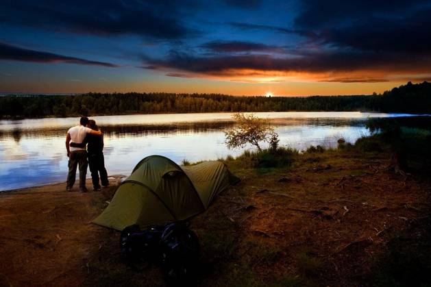 A pair of campers with a tent set against a beautiful sunset lake landscape model released Symbolfoto Copyright: xleafx Panthermedia68321128.jpg