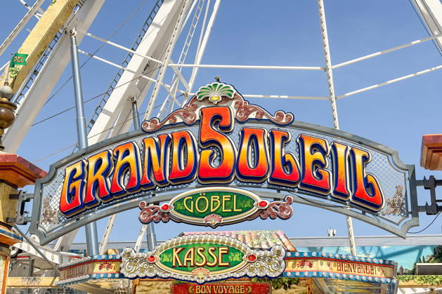 Freiburg im Breisgau GER, Jahrmarktbesuch, Freiburg im Breisgau, 24.05.2026 Das farbenfrohe Schild des Riesenrads Grand Soleil von Göbel mit den Aufschriften Kasse , Bienvenue! und Bon Voyage! ist vor klarem blauem Himmel zu sehen. Copyright: xEibner-Pressefoto ThomasxHessx