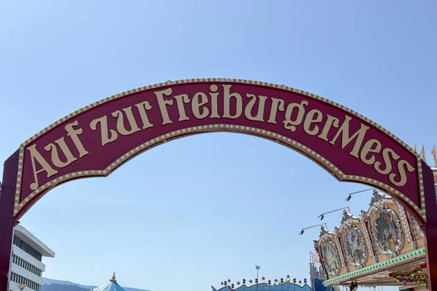 Freiburg im Breisgau GER, Freiburger Mess, Freiburg im Breisgau, 24.05.2026 Der Eingangstorbogen zur Freiburger Mess unter blauem Himmel, flankiert von einem modernen Gebäude und einem Karussell. Copyright: xEibner-Pressefoto ThomasxHessx