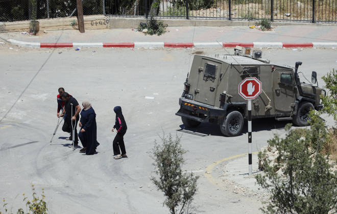 Israeli Demolition West Bank Family Displaced Eid Al-Adha Residents, including a man using a crutch and a medical worker, walk past an Israeli military vehicle in Nahhalin, occupied West Bank, on May 25, 2026, after a demolition operation. The demolition, carried out by Israeli forces who stated the structure was built without a permit, displaced an eight-member Palestinian family just two days before the Islamic holiday of Eid al-Adha. Bethlehem West Bank Palestinian Territories Copyright: xMosabxShawerx