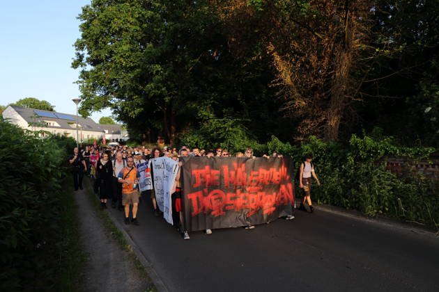 Demonstranten laufen mit Banner Die Häuser denen, die sie brauchen in der Straße Alter Tornow auf der Halbinsel Hermannswerder während einer Demonstration gegen die Räumung des ehemals besetzten Hauses Tornowstraße 40, Potsdam, 26. Mai 2026. Hausbesetzer-Demo in Potsdam