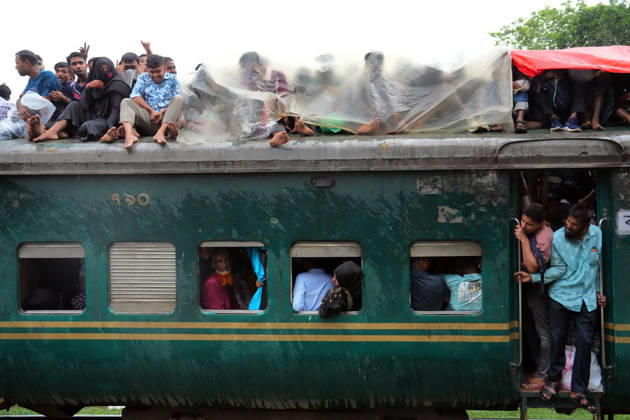May 27, 2026, Joydevpu, Gazipur, Bangladesh: Ahead of Eid al-Adha, passengers traveling on the roof of an overcrowded train from Joydebpur in Gazipur, Bangladesh, cover themselves with plastic sheets to protect against heavy rain as they journey back to their village homes. Many of the passengers are low-income garment workers who endure these dangerous travel conditions due to the affordable fare. Joydevpu Bangladesh - ZUMAk174 20260527_zip_k174_011 Copyright: xSyedxMahabubulxKaderx