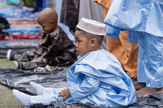 May 27, 2026, New York, New York, USA: A child seen playing as men pray with Mayor Zohran Mamdani during Eid Al-Adha holiday prayers at The Yancy Track & Field in New York, NY on May 27, 2026. Hundreds of men, women and children attended wearing clean, colorful and expensive traditional clothes. Eid al-Adha translates from Arabic to Festival of Sacrifice is one of the most important holidays in the Islamic calendar. It honors the Prophet Ibrahim s (Abraham s in Judaism) absolute obedience to God, commemorating his willingness to sacrifice his son as an act of submission before God provided a ram to sacrifice instead. New York USA  - ZUMAr339 20260527_znp_r339_049 Copyright: xLevxRadinx