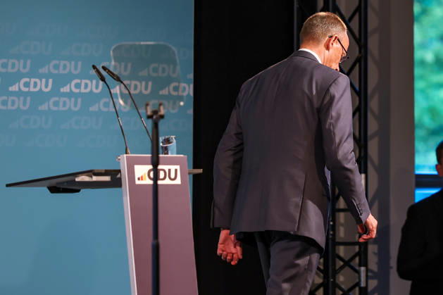 27.05.2026, Politik, Bundeskanzler Friedrich Merz (CDU) verlässt nach seiner Rede mit hängendem Kopf die Bühne zu Gast als Festredner beim Festakt in der Schützenhalle Hüsten bei Arnsberg. 80 Jahre Neheim-Hüstener Programm. Nordrhein-Westfalen Deutschland