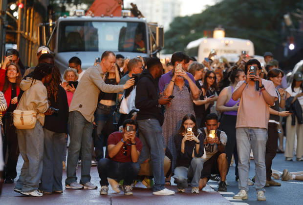 Revelers holding cameras and cell phones stand on 42nd street with moving traffic for a Manhattanhenge sunset event in New York City on Thursday, May 28, 2026. The Manhattanhenge sunset comes twice a year when the setting sun aligns precisely with Manhattan s street grid.  NYP20260528208 JohnxAngelillo
