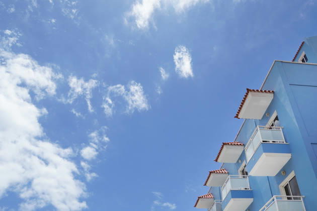 Thema Sonne, Strand und Meer, modernes Hotel und Schönwetterwolken aus der Untersicht als Symbolbild für Sommerurlaub am Meer, Strandurlaub, All Inclusiv Urlaub, z.B. Kanaren, Mittelmeerinseln