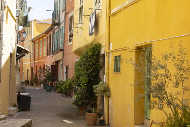 Villefranche sur Mer Frankreich 31052026 - Gasse in der Altstadt von Villefranche-sur-Mer, Cote d Azur (Côte d Azur), Suedfrankreich. Bunte Hausfassaden in Ocker, Gelb und Rosa, enge Treppengasse, Frau als Passantin. Departement Alpes-Maritimes. Villefranche sur Mer Departement Alpes-Maritimes Frankreich