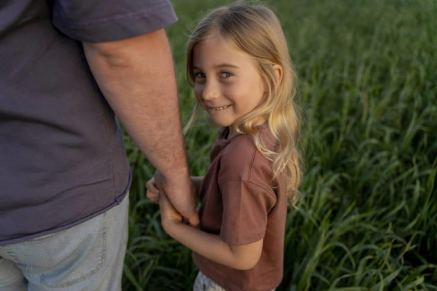 Father and daughter holding hands in green field smiling model released, Symbolfoto, OGSF00315