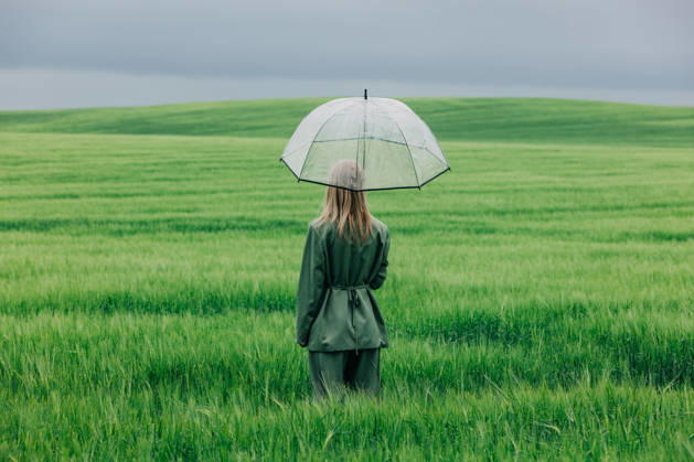 Woman standing in green wheat field with transparent umbrella in the rain model released, Symbolfoto, VSNF04975