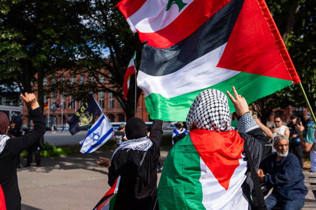 June 5, 2026, Berlin, Berlin, Germany: A participant draped in a Palestinian flag raises a peace sign during a Naksa Day demonstration at Neptunbrunnen in Berlin, Germany while in the background Israel supporter can be seen. Berlin Germany - ZUMAc291 20260605_zip_c291_004 Copyright: xMariaxCastrox