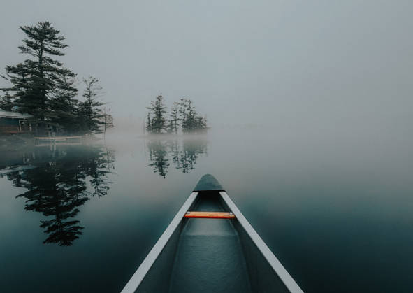Canoe glides across a still lake in heavy fog in early morning Buck Lake, Ontario, Canada CR_DOHO260604G-2040778-01
