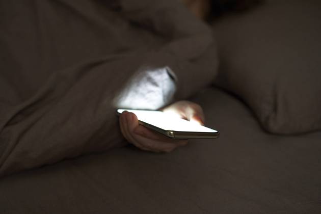 Weibliche Hand mit Smartphone, das im dunklen Schlafzimmer unter der Decke leuchtet Female hand holding smartphone glowing under blanket in dark bedroom setting Copyright: imageBROKER ElenaxSafonova ibxiqx17850741.jpg