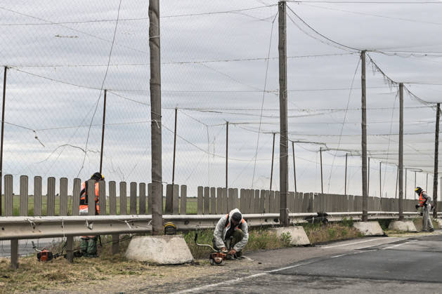RECORD DATE NOT STATED Municipal workers mow grass along the roadside of the Mykolaiv–Kherson highway, above which anti-drone netting has been installed to protect against Russian FPV drones, Kherson region, Ukraine, on June 3, 2026. The Russian army attacks the city daily with FPV drones and other unmanned aerial vehicles, deliberately terrorizing civilians. Russian forces conduct hunts for local residents, tracking them with FPV drones and dropping explosives. Police officers, medics, public transport, and urban infrastructure are also targeted (Photo by Dmytro Smolienko Ukrinform) Life under shelling in frontline Kherson Copyright: xDmytroxSmolienkox