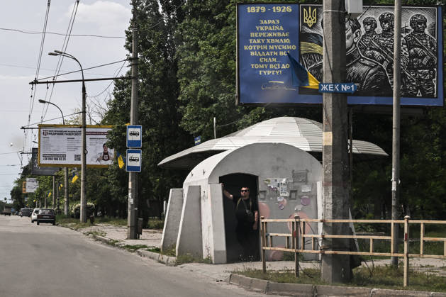 RECORD DATE NOT STATED A man stands at the entrance to a mobile concrete shelter installed at a public transport stop in the frontline city of Kherson, Ukraine, on June 2, 2026. The Russian army attacks the city daily with FPV drones and other unmanned aerial vehicles, deliberately terrorizing civilians. Russian forces conduct hunts for local residents, tracking them with FPV drones and _drop_ping explosives. Police officers, medics, public transport, and urban infrastructure are also targeted. Based on the intensity of attacks, Kherson is informally divided into yellow and red zones, with the red zone considered the most dangerous due to constant shelling and drone strikes. Anti-drone netting has been installed above roads to help protect against Russian Copyright: xDmytroxSmolienkox