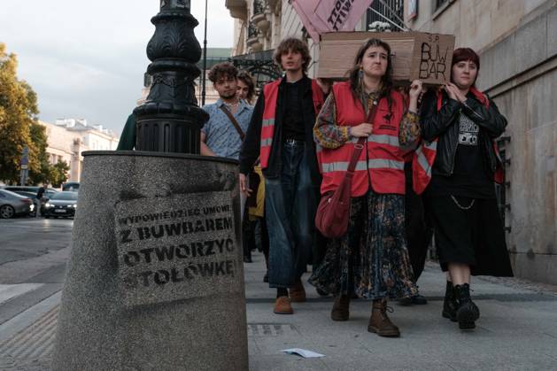 June 12, 2026, Warsaw, Masovian Voivodeship, Poland: Student activists carry a symbolic cardboard coffin and white flowers during a mock funeral procession doubling as a students demonstration welcoming the recent closure of the University of Warsaw s premium food hall, BUWBAR, located in the main library on campus. The establishment closed suddenly after only a month of operation following intense protests by students, who were promised an affordable student s canteen by the university s rector but were instead given an expensive food hall offering premium meals beyond student budgets. The graffiti on the trash bin on the left reads terminate the contract with BUWBAR and open a canteen! Warsaw Poland - ZUMAk204 20260612_zip_k204_030 Copyright: xRomanxKozielx