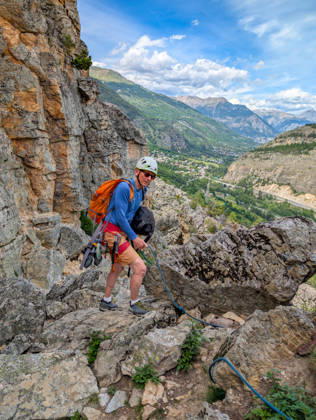 Klettern in Casse de Prelles in den französischen Alpen. Eine Person mit Kletterausrüstung auf einem felsigen Bergpfad. Alpines Bergpanorama unter einem blauen Himmel